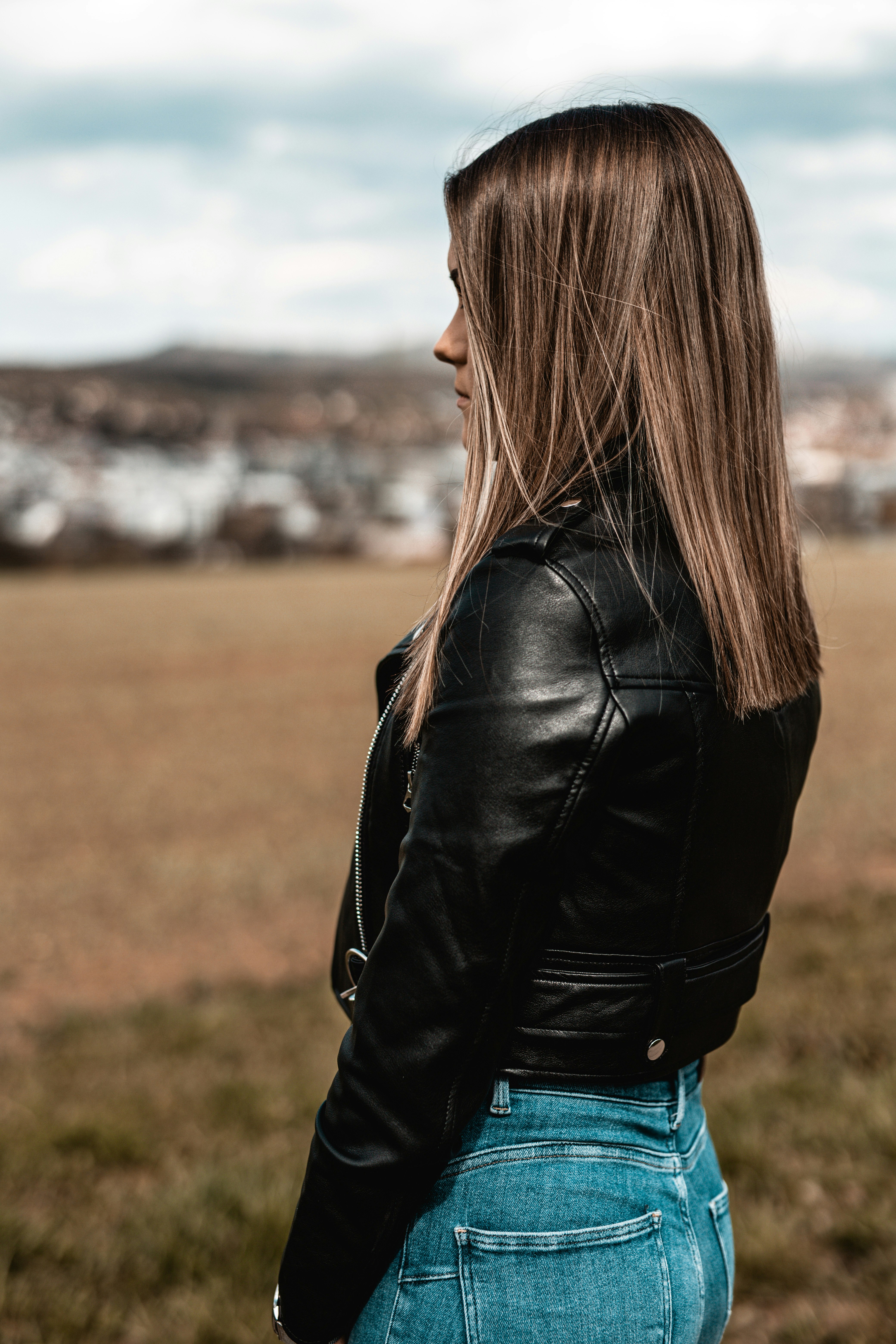 woman in black leather jacket standing on green grass field during daytime